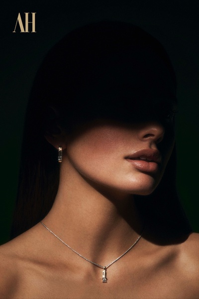 A high-contrast, moody close-up photograph showcasing a delicate necklace and earring set, emphasizing textures and clean design.