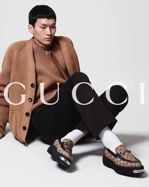 A high-end studio shot of a model wearing patterned loafers, utilizing a neutral color palette and clean, balanced composition.