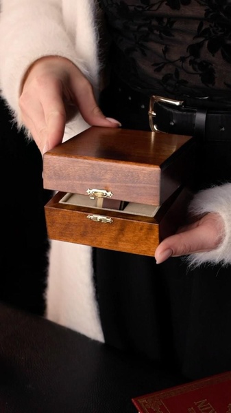 A close-up, high-definition shot featuring a person holding a premium wooden jewelry box, highlighting the craftsmanship and tactile quality of the product.