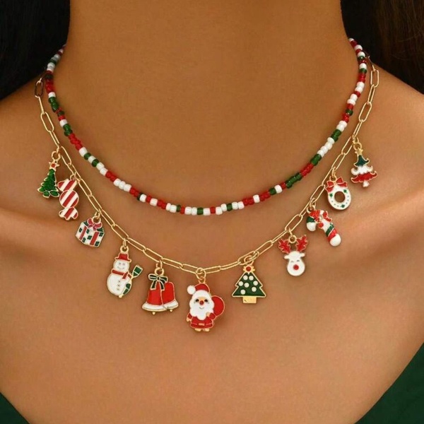 A close-up, high-detail product shot featuring a multi-layered Christmas-themed charm necklace on a model. The design highlights seasonal iconography like Santa, snowmen, and Christmas trees in a clean, professional aesthetic.