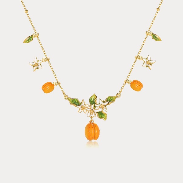 A high-quality 1:1 studio shot of a gold necklace featuring orange fruit and flower charms, set against a clean, neutral background.