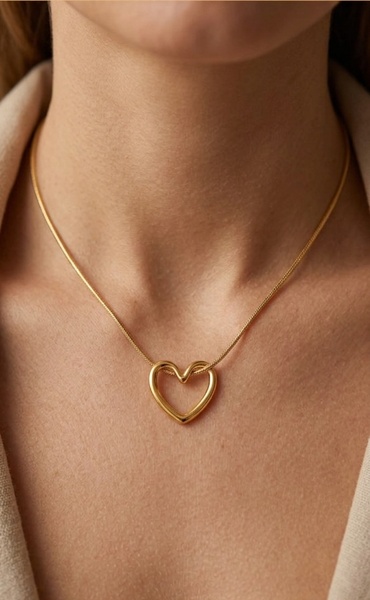 A close-up, high-detail shot of a minimalist gold heart pendant on a delicate chain against a soft neutral background.