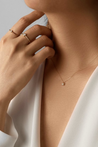 A close-up, high-end studio shot of a gold necklace and stacked rings, focusing on elegance and product texture.