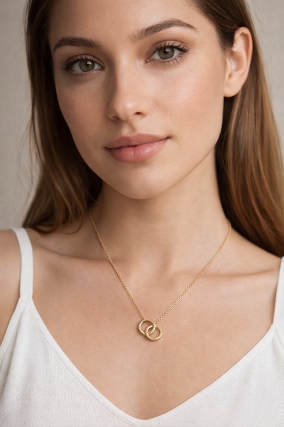 A close-up, high-key portrait focusing on a gold necklace, emphasizing clean skin textures and a neutral, minimalist aesthetic.