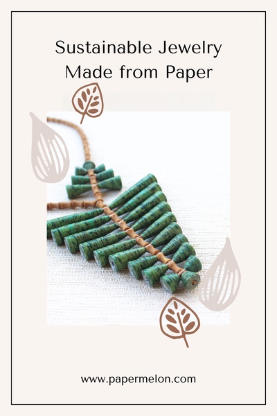 A clean, minimalist product hero shot featuring a handcrafted green paper necklace against a textured white background, accented with simple botanical leaf illustrations.