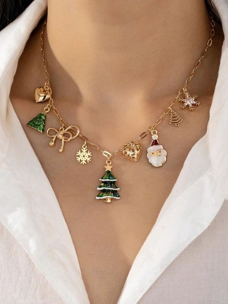 A close-up aesthetic shot of a gold-toned necklace featuring festive charms like Santa, Christmas trees, and snowflakes.