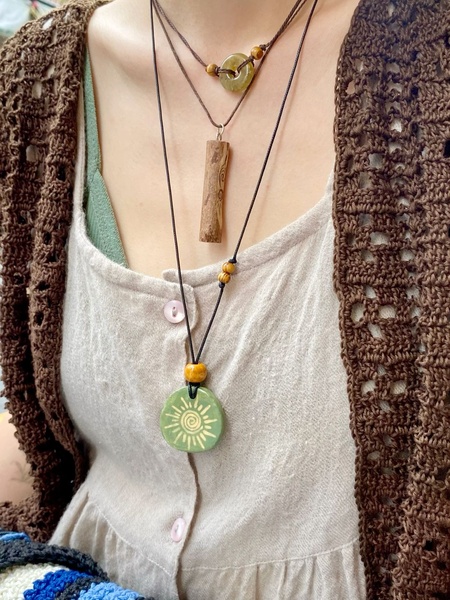 A close-up aesthetic shot featuring a triple-layered necklace set displayed on a model wearing a crochet top.