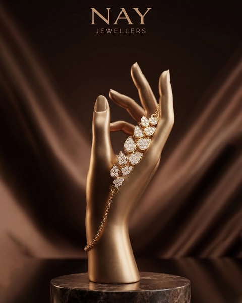 A high-end product display showcasing a gold-plated bracelet on a gold mannequin hand against a dark, draped silk background.
