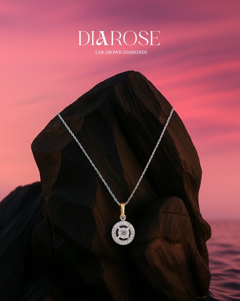 A high-end diamond pendant necklace rests on a dark rock formation against a striking, vibrant sunset sky.