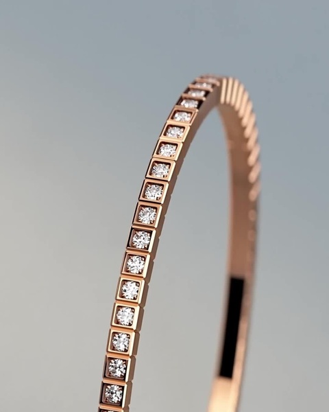 A close-up, high-definition side profile of a rose gold diamond bangle, highlighting the craftsmanship and shimmering stone settings against a neutral background.