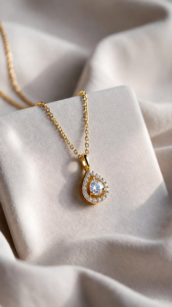 A high-end, close-up product photograph of a gold diamond-encrusted pear-shaped pendant necklace draped over a draped, neutral fabric.