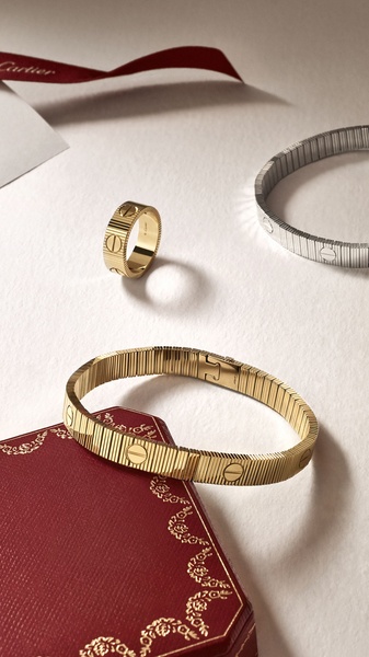 A refined product hero shot featuring a gold bracelet, a matching gold ring, and a secondary silver bracelet laid against a classic red jewelry box.