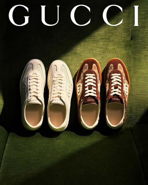 A high-end, top-down product shot featuring two colorways of a luxury sneaker on a textured green background, emphasizing symmetry and clean composition.
