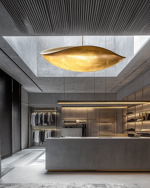 A high-end retail clothing store interior featuring soft warm accent lighting, concrete textures, and elegant clothing displays.