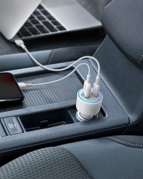A high-quality lifestyle shot showing a dual-port car charger powering devices in a modern vehicle interior.