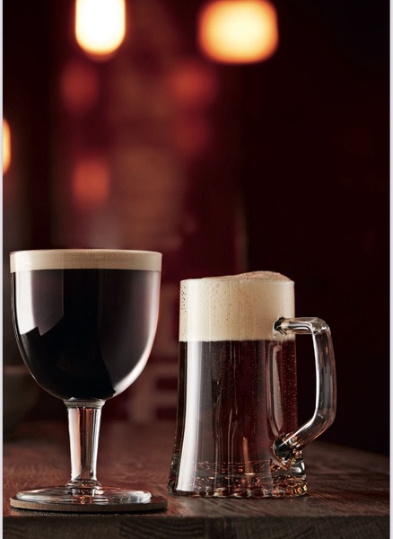 A high-contrast, moody product shot featuring a glass of dark beer and a matching beer mug on a wooden table, emphasizing texture and premium quality.