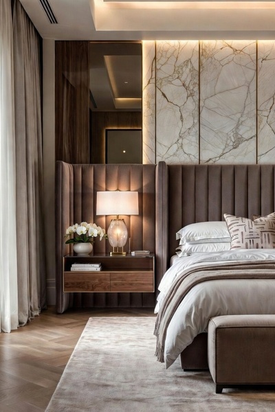 A high-end bedroom scene featuring an upholstered bed with vertical channel tufting, marble wall accents, and warm, sophisticated ambient lighting.