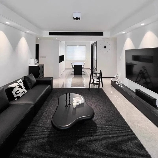A high-end interior design shot showcasing a low-profile coffee table in a stark, black-and-white modern living room.
