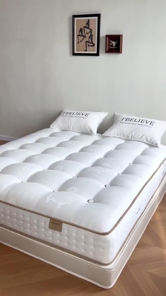 A clean, high-end studio shot of a white mattress in a neutral-toned bedroom, focusing on quality and simplicity.