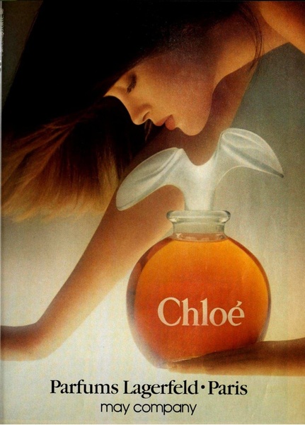 A close-up aesthetic shot of a perfume bottle held by a model with a soft-focus, dreamlike lighting treatment.