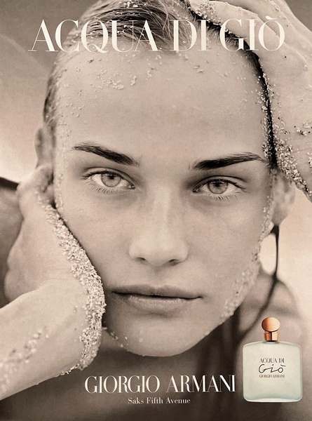 A high-fashion, grainy black and white portrait featuring a model covered in sand, emphasizing natural beauty and sensory texture for a fragrance brand.