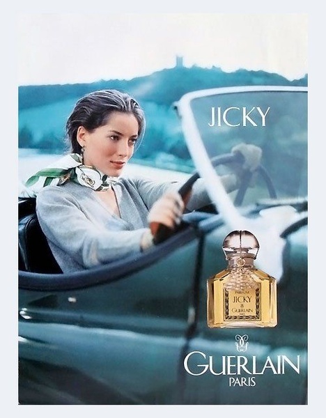 A refined, lifestyle-focused ad for a high-end perfume, featuring a woman in a convertible to signify timeless elegance.