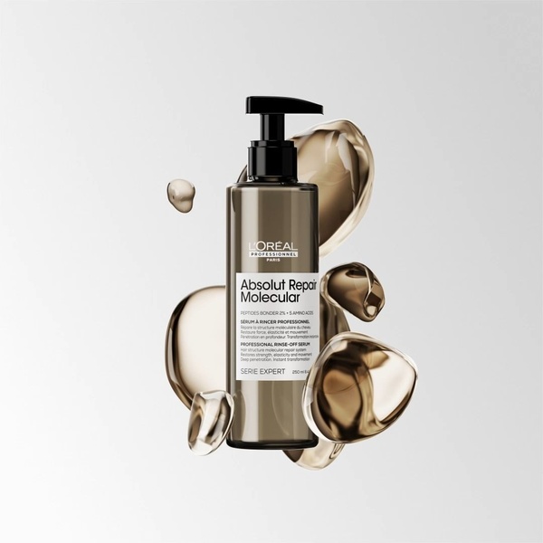 A high-end product hero shot featuring a hair serum bottle surrounded by floating, translucent liquid spheres against a clean gray background.