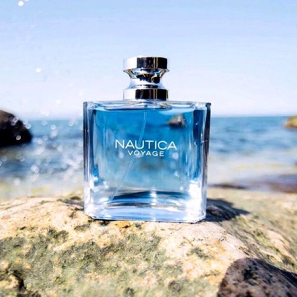 A high-quality product image of a perfume bottle placed on rocks against a backdrop of the ocean, emphasizing freshness and travel.