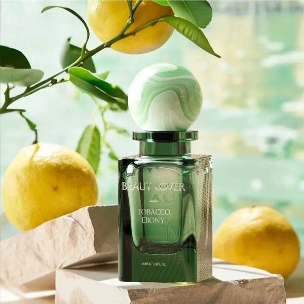 A high-quality product hero shot featuring a perfume bottle centered on stone blocks surrounded by fresh lemons and foliage.