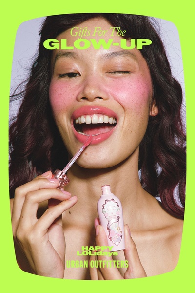A festive, high-energy creative showcasing a lip gloss product with bright, neon-toned color-blocking and celebratory holiday messaging.