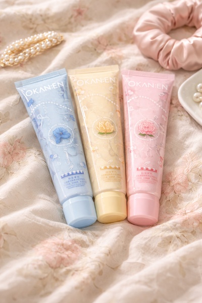 A high-quality, soft-focus product photography shot displaying three tubes of facial cream in aesthetic colors on a textured fabric surface.