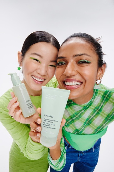 A bright, high-energy studio shot featuring two smiling models holding the product, emphasizing a natural, friendly brand aesthetic.