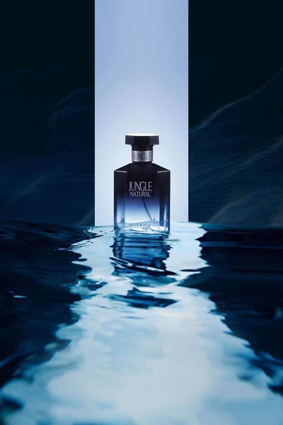 A high-contrast hero shot of a perfume bottle emerging from dark water with a clean geometric light background.