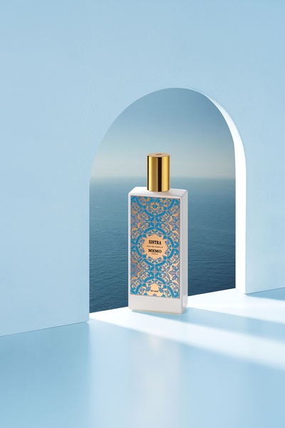 A luxury perfume bottle framed by a clean white archway against a calm sea background, highlighting premium branding and minimalist aesthetics.