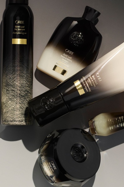 A high-end, studio-lit flat lay composition featuring the full Gold Lust hair care range on a neutral background.