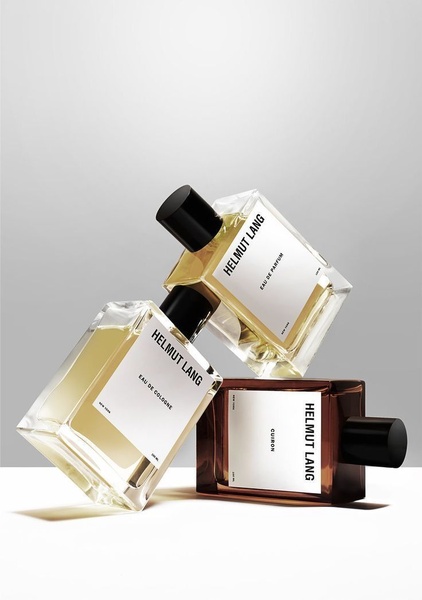 A high-end editorial product shot featuring three cologne bottles stacked in a triangular arrangement against a clean, neutral studio background.