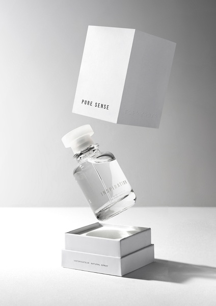 A high-end, minimalist studio product shot featuring a perfume bottle and its packaging floating mid-air against a soft grey background.
