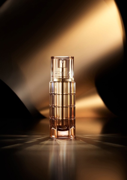 A high-end product shot of a luxury serum bottle centered in dramatic golden lighting, emphasizing a premium and sophisticated brand aesthetic.