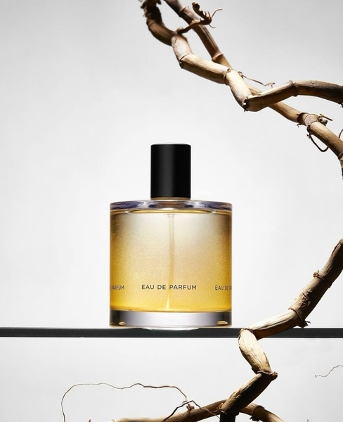 A high-end studio capture of a perfume bottle against a neutral backdrop with a sculptural wooden element to convey luxury and natural ingredients.