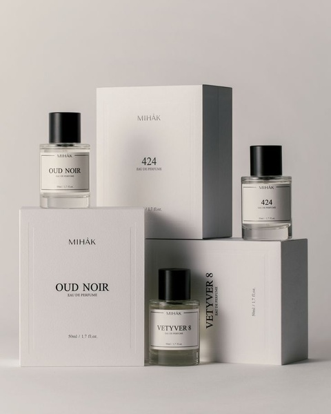 A high-end editorial display featuring three perfume bottles and their corresponding packaging on a neutral grey background.