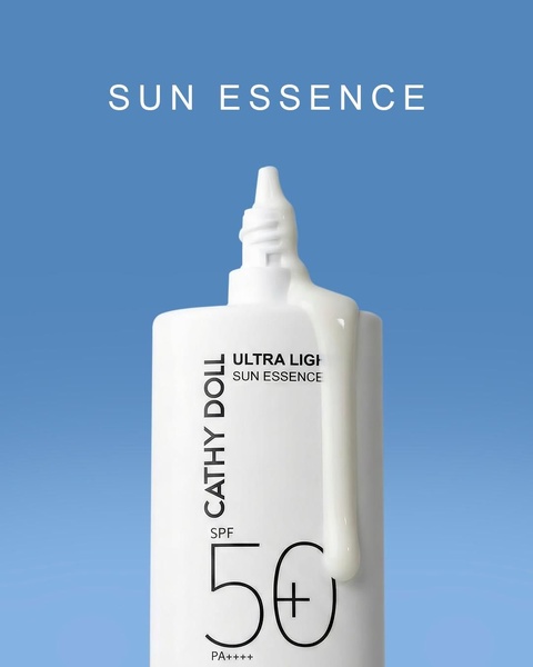A high-key, minimalist product shot featuring a sun essence bottle with a fluid texture drop against a gradient blue backdrop.