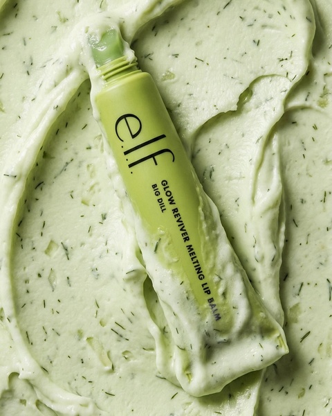 A high-impact, top-down product shot of a tube of lip balm sitting in a matching green, textured cream base.
