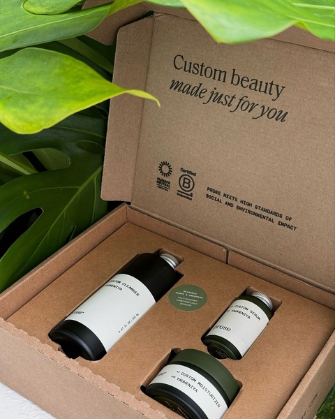 A high-quality, top-down shot of a personalized skincare product kit featuring a cleanser, serum, and moisturizer inside branded eco-friendly packaging.