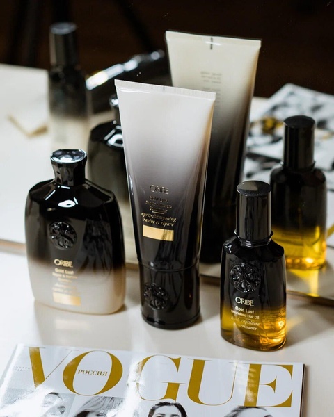 A high-end, editorial-style composition featuring a collection of hair care bottles arranged on a surface with a fashion magazine.