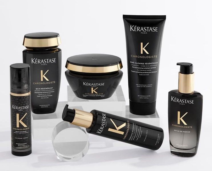 A high-end studio product collection shot showcasing a full range of hair care bottles and jars arranged on transparent platforms against a clean white background.