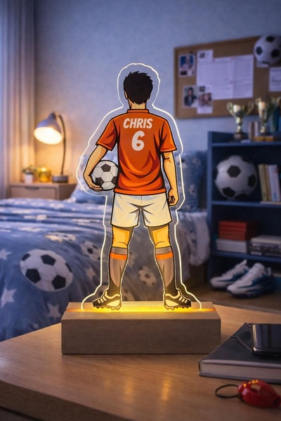 A customized acrylic LED night light shaped like a soccer player on a wooden base, featuring the name CHRIS and jersey number 6.