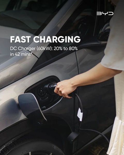 A close-up, high-trust demonstration showing a consumer plugging a charger into an electric vehicle, highlighting specific charge times.