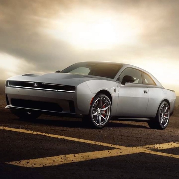 A high-contrast hero shot of a modern silver electric coupe parked on a minimalist asphalt surface at sunset.