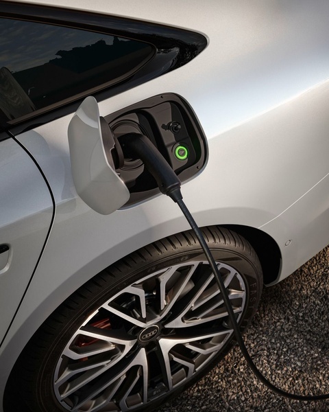 A close-up photograph of a charging cable plugged into a modern electric vehicle, focusing on the interface connection.