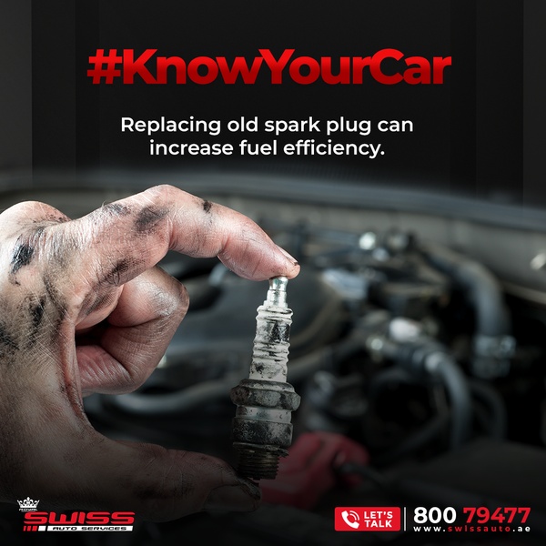 A close-up of a dirty, used spark plug held by a mechanic to emphasize the importance of regular vehicle maintenance.